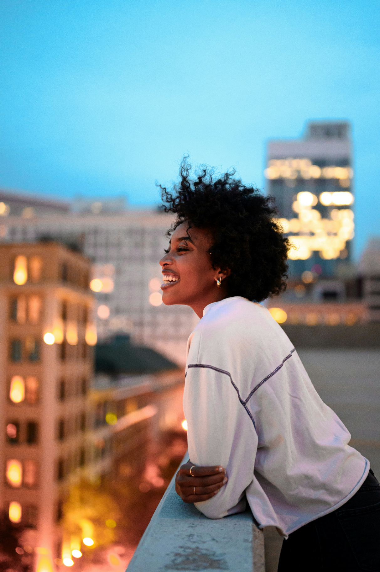 Woman smiling against a city skyline at dusk
